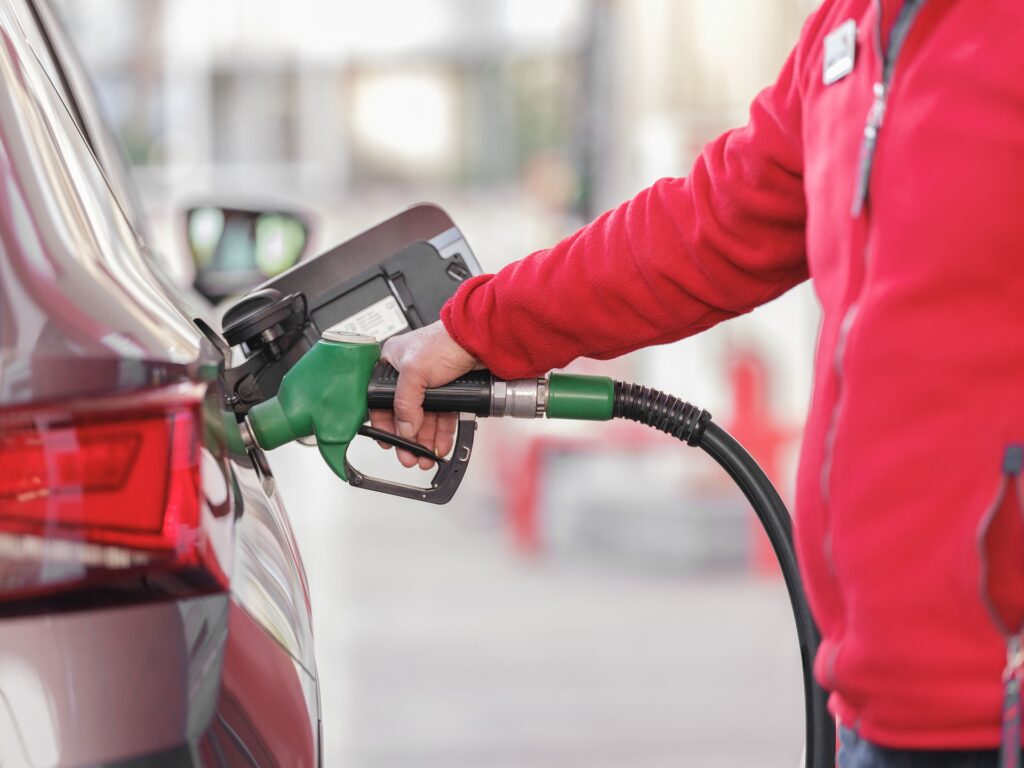 Un empleado de una estación de servicio carga combustible en un auto
