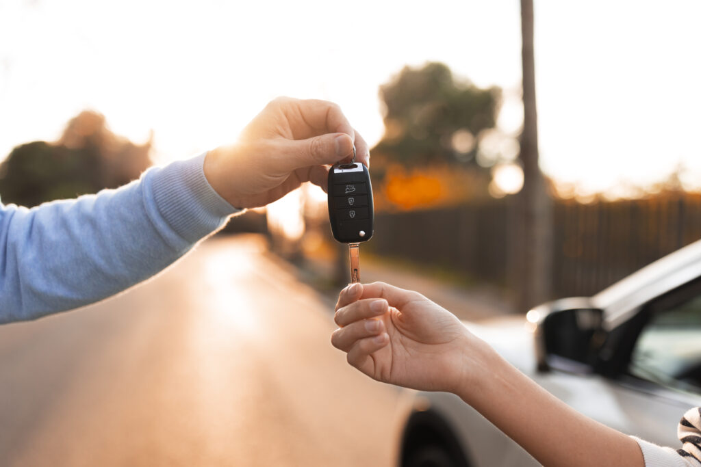 Persona entregando llaves de auto a otra. 